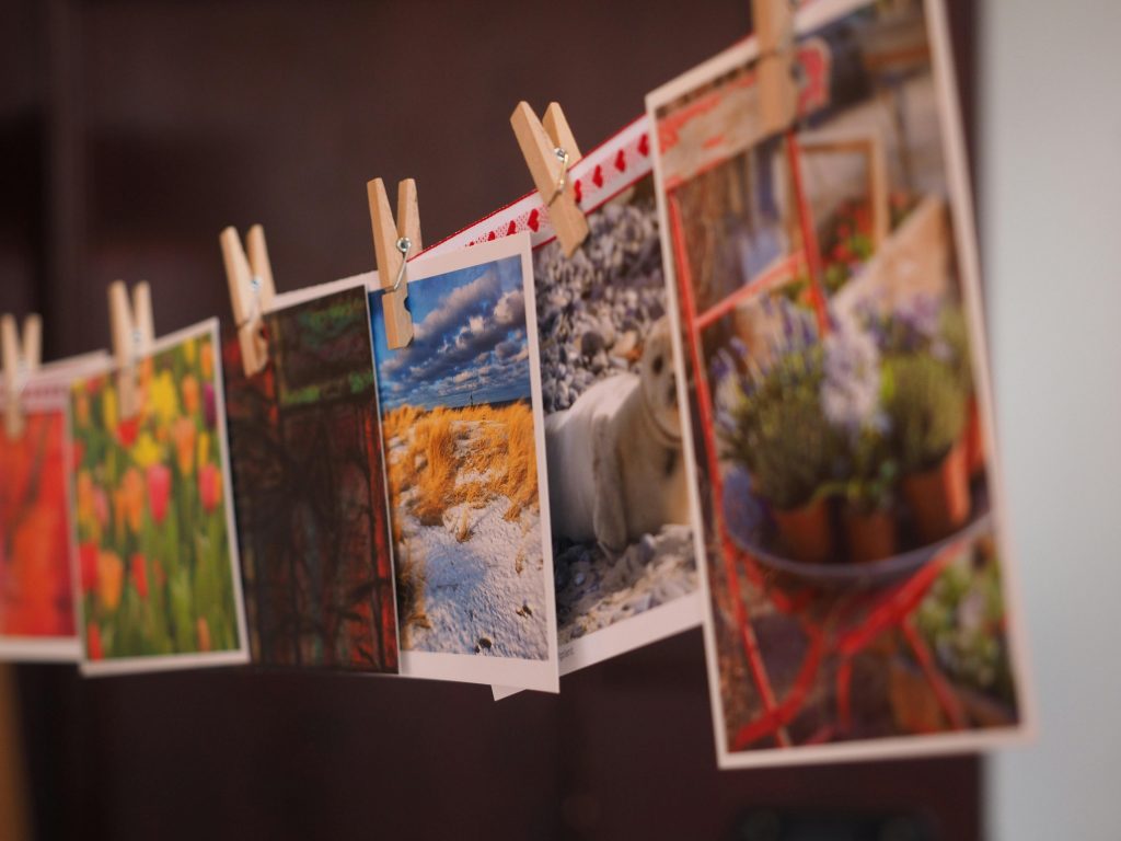 Erfahrungen Colorful photographs and postcards clipped with wooden pins in a creative indoor arrangement.